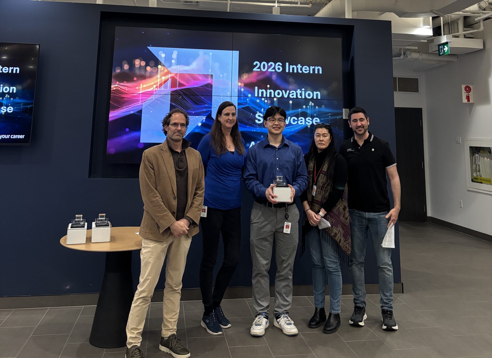 Vincent holding the award with four judges in front of the Intern Innovation Showcase screen